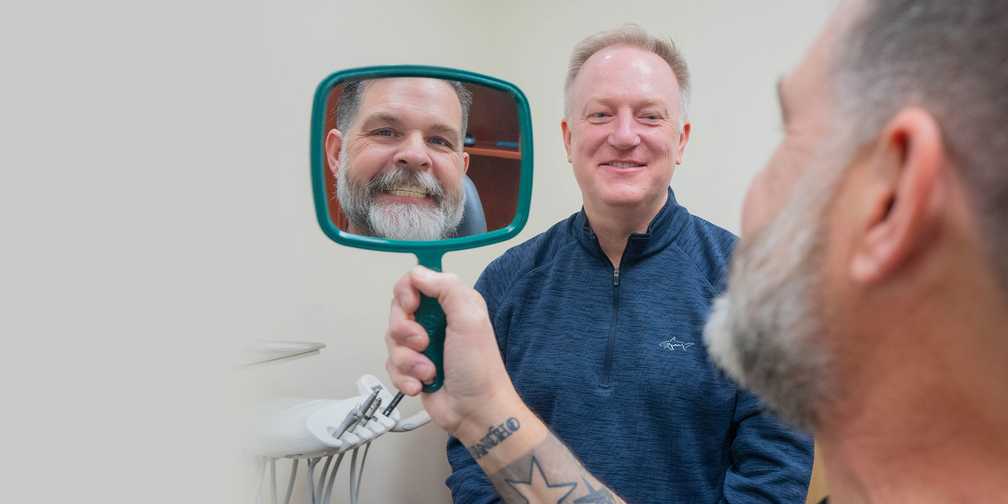 patient holding mirror looking at their new smile